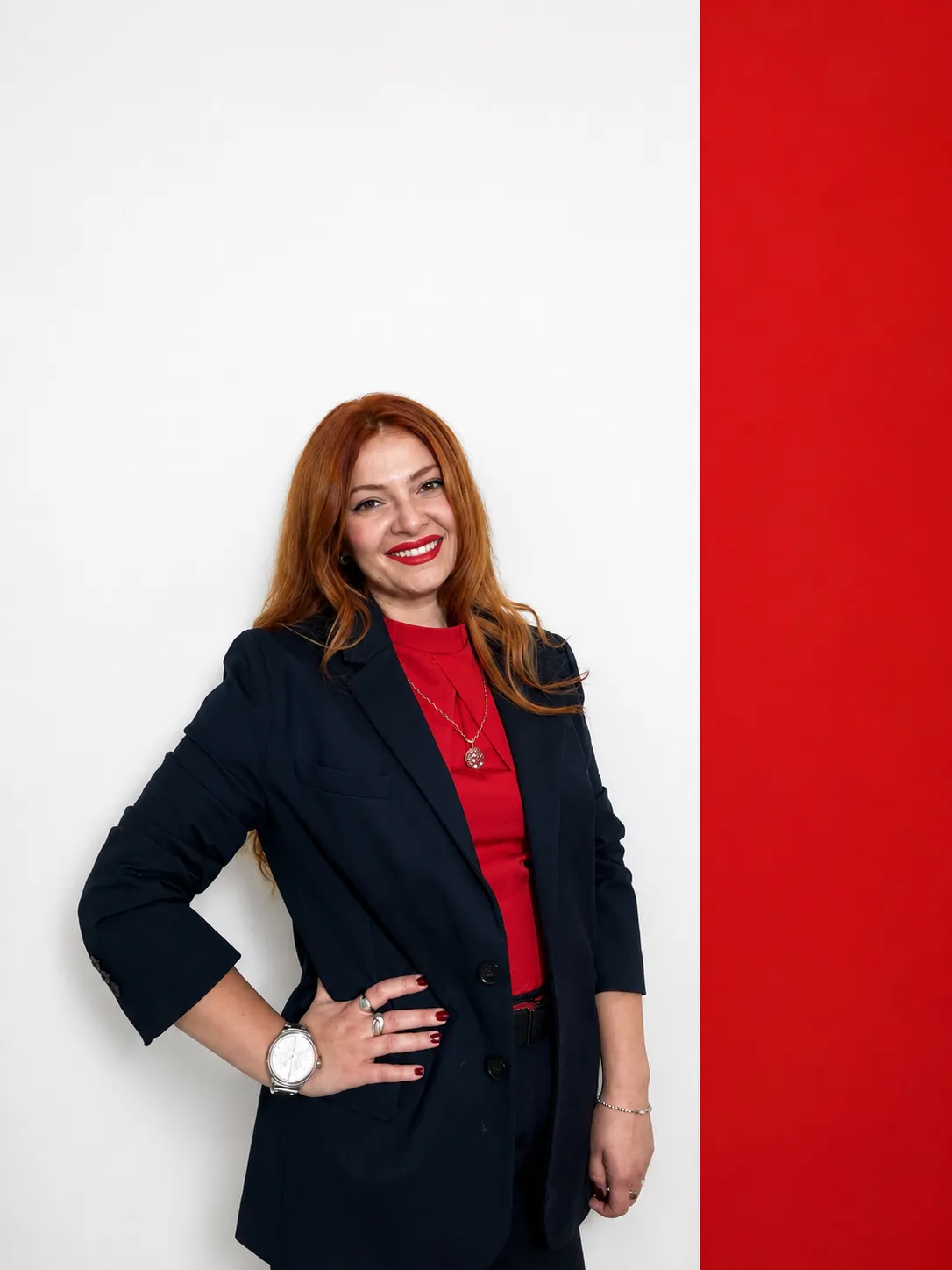 Oksana Nasadiuk standing with one hand on her hip, beside a red wall